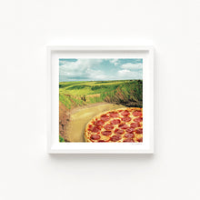 Load image into Gallery viewer, A surreal art print of a pepperoni pizza seamlessly blending into a coastal bay landscape with rolling green cliffs and a sandy shore. Coastal Art