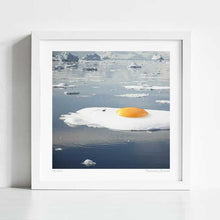 Load image into Gallery viewer, Surrealist artwork titled "Egg-berg" featuring a sunny-side-up egg on a melting iceberg. This piece by Vertigo Artography combines environmental themes with whimsical imagery, perfect for contemporary art collectors. Explore the fusion of reality and imagination with "Egg-berg," a striking addition to any modern art collection. Buy now to own a piece that sparks conversation and visual delight.